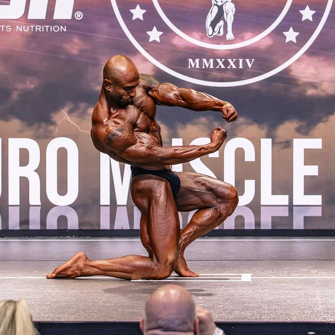 Coach Hassan Ibrahim posing on stage at a competition
